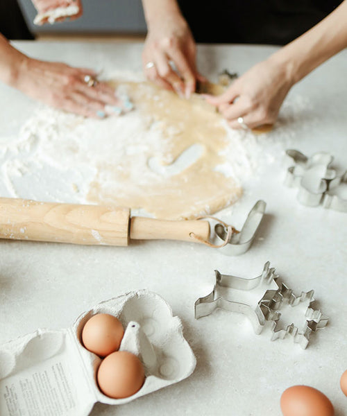 Two bakers cut out pieces of dough to make family friendly biscuits.