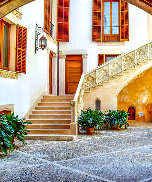 Interior Spanish style courtyard with long lush green foliage potted plants.