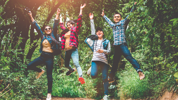 Happy group of teens jumping up in forest setting