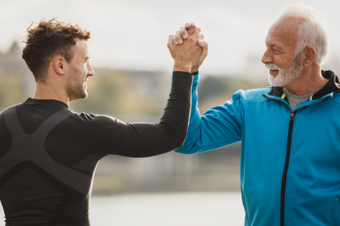 Younger and older man high five while working out