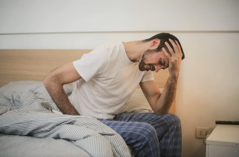 Young man in sleepwear waking up and feeling under the weather