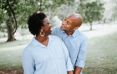 A Black couple poses in a park, looking into each other's eyes smiling