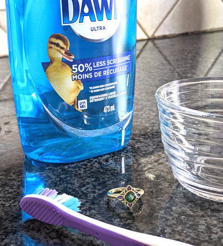 Gold ring cleaning supplies: glass bowl, dawn dish soap, and a toothbrush