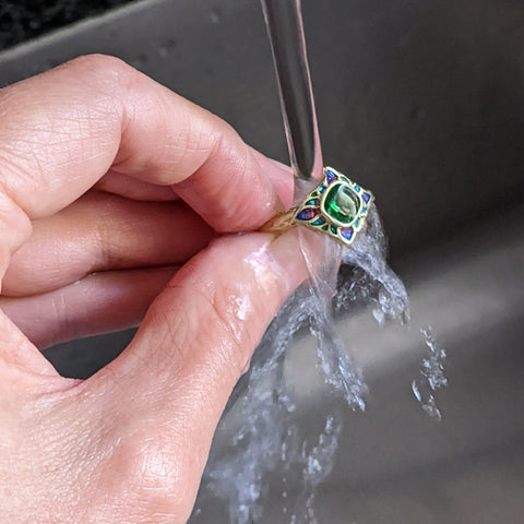 Rinsing a gold ring in clean water after cleaning it in soapy water