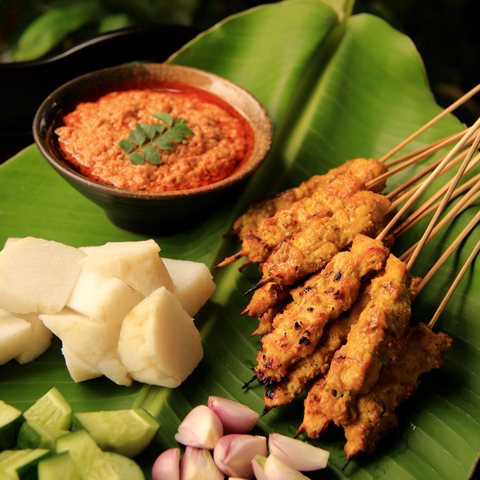 chicken satay sticks served with peanut dipping sauce and vegetables