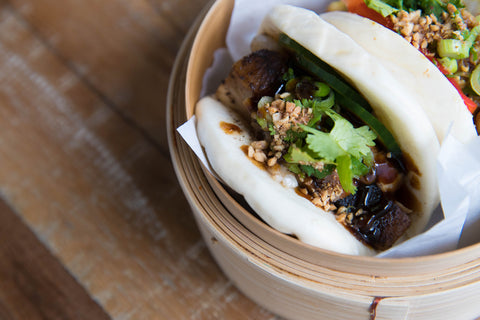 Steamed lotus buns also known as bao buns with meat and coriander in a bamboo steamer