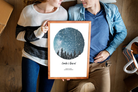 un couple tient une affiche de carte des étoiles personnalisée qui montre le ciel étoilé à leur premier rendez-vous