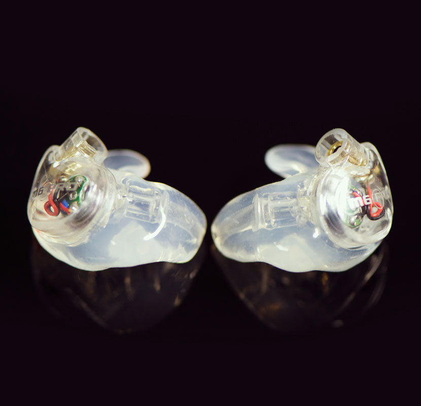 Pair of clear M6 PRO 1st generation earpiece with clear custom eartips on a shiny black background