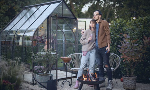 couple standing by the backyard greenhouse