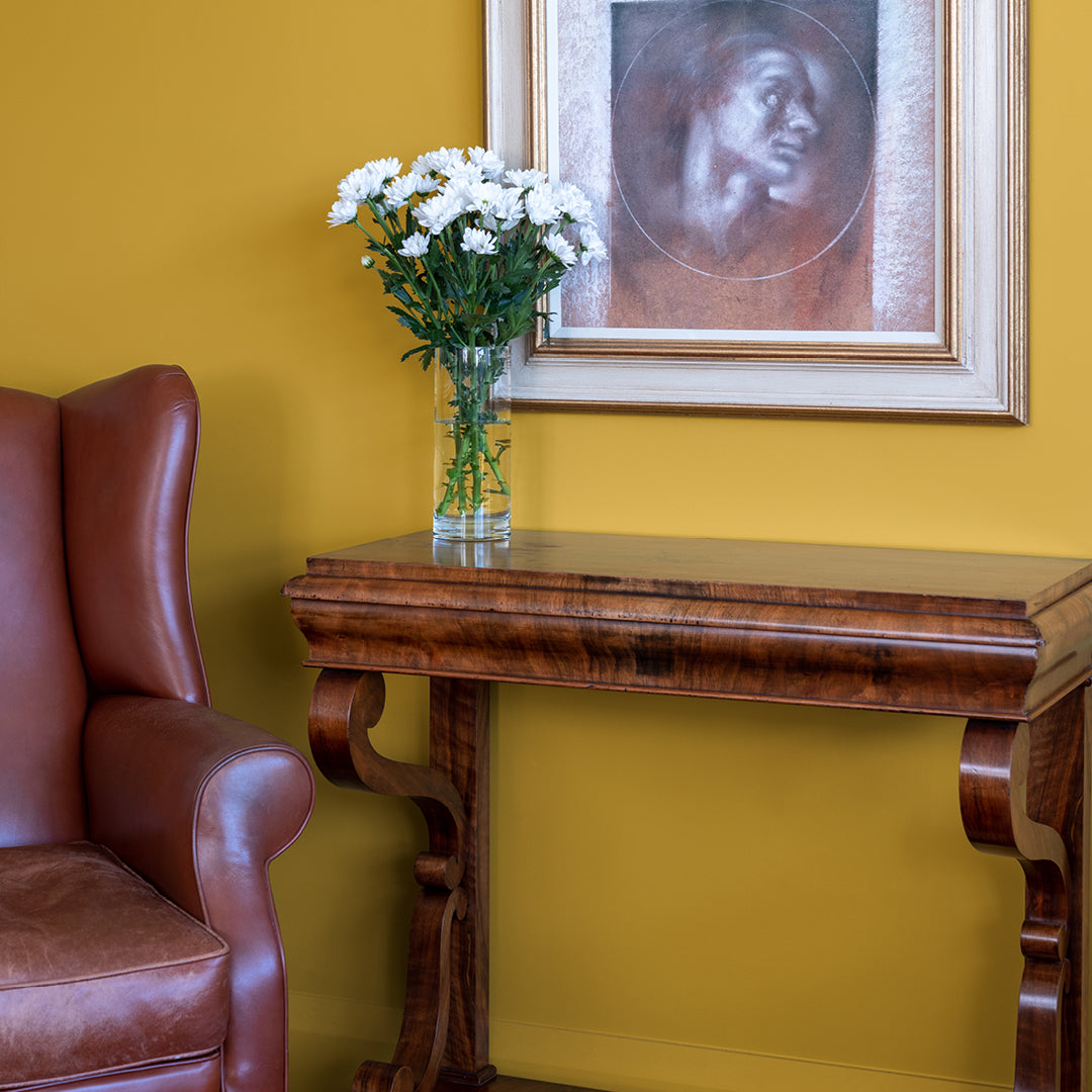 Brushed Gold painted wall with brown leather chair and dark wooden table