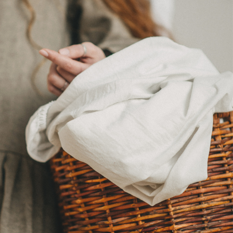 woman carrying linen sheets using a woven hamper