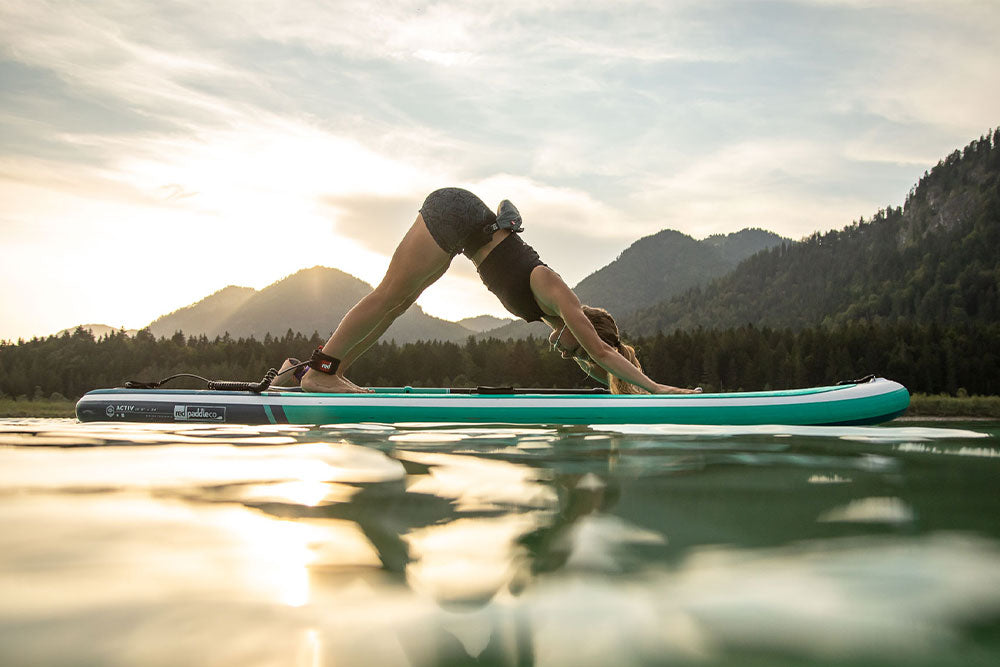 Woman in Downward Dog pose on a paddle board