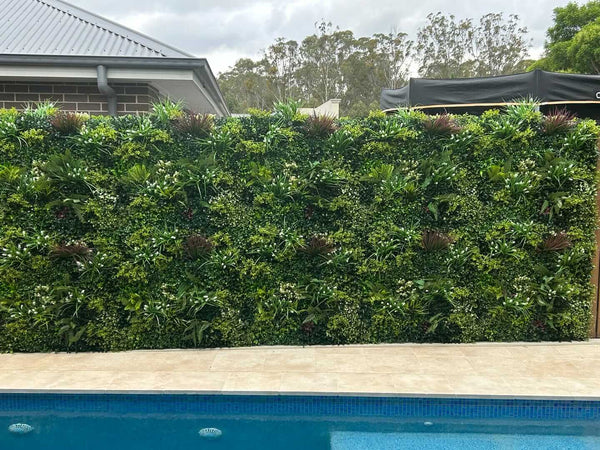 Lush spring artificial green wall panel installed along a pool