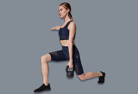 female athlete doing a lunge holding a kettlebell wearing stabilyx ventilator shorts and xtra support sports bra in true navy