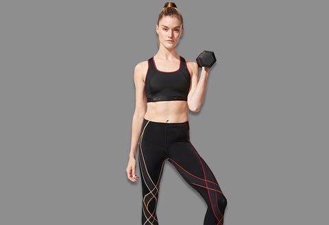 female athlete doing a hammer curl holding a dumbbell wearing endurance generator tights in black/gradient rooibos and xtra support sports bra