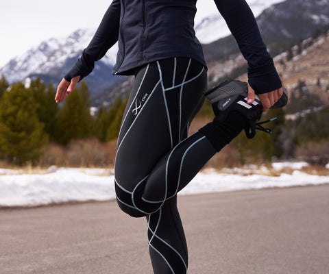 female athlete stretching leg before a day of skiing in endurance generator insulator tights