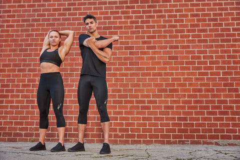 woman and man stretching after workout wearing CW-X compression clothing