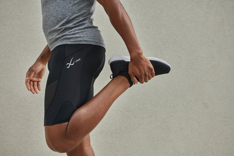 man stretching his quad after a workout wearing CW-X compression shorts