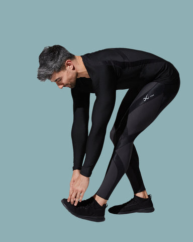man stretching his legs after a workout wearing CW-X compression pants