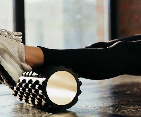 athlete rolling out her leg post run with a foam roller