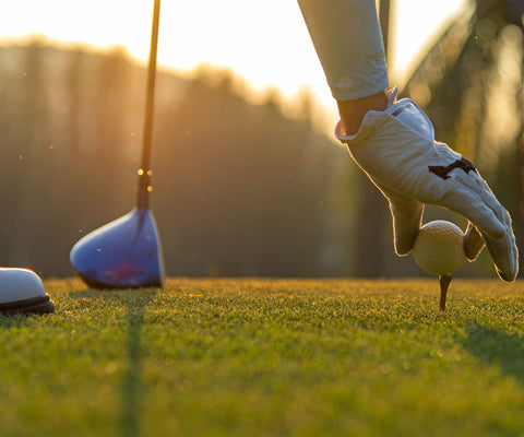 golfer putting down golf ball on tee getting ready to hit the ball