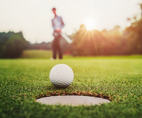 image of golf ball with golfer in background