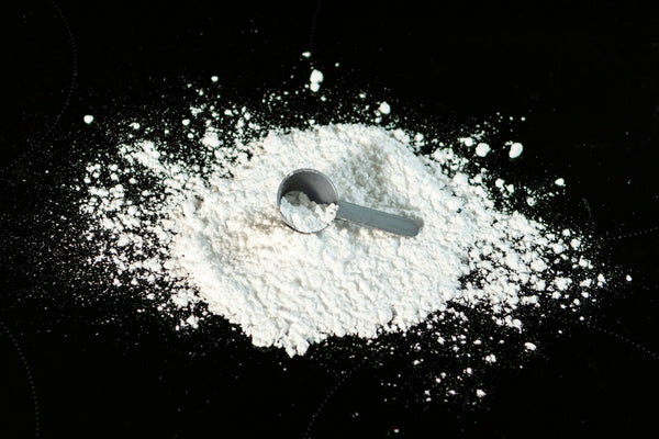 creatine powder and scoop on a black background