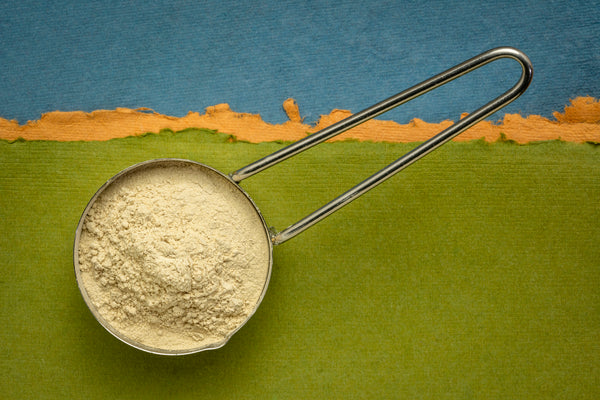 ashwagandha root (aka Indian ginseng) powder in a measuring metal scoop against handmade paper