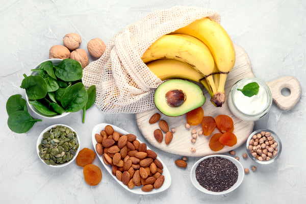 a variety of healthy natural foods including spinach, bananas, avocado, nuts, eggs