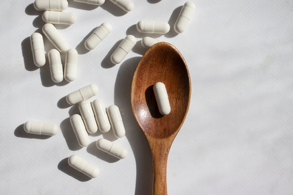 probiotic capsules on a gray background with a wooden spoon