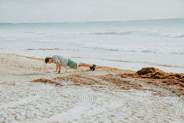 man doing pushups on the beach