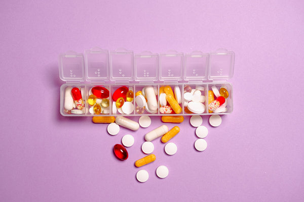 vitamins in an organized container for travel sitting on a light purple background