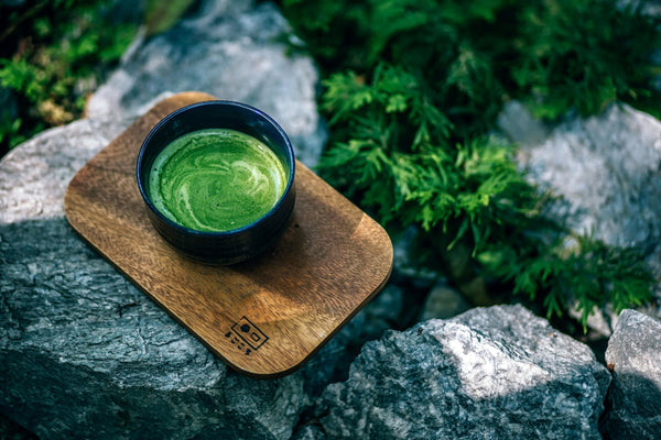 matcha tea on a wooden board outside in nature on rocks