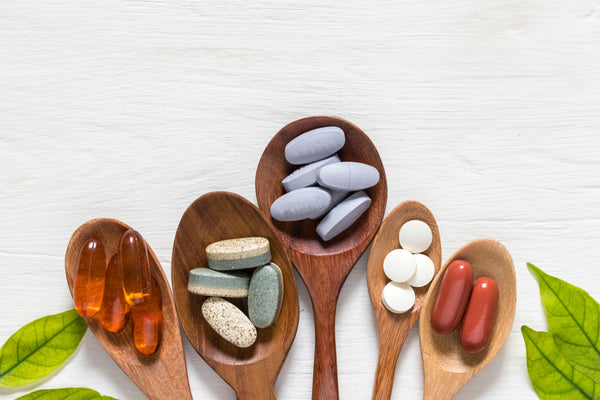 a variety of supplements sitting on wooden spoons