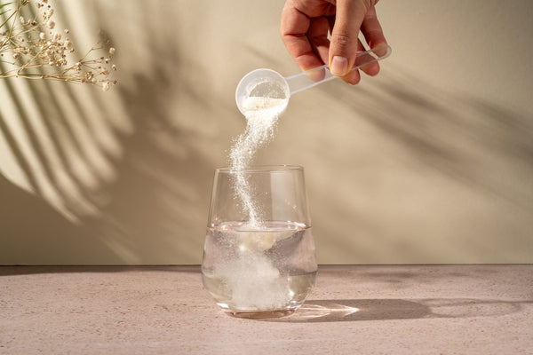 collagen powder being poured into a glass of water