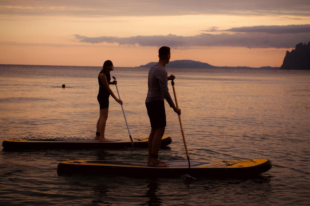 Couple paddle boarding during sunset. Photo by Trarete.
