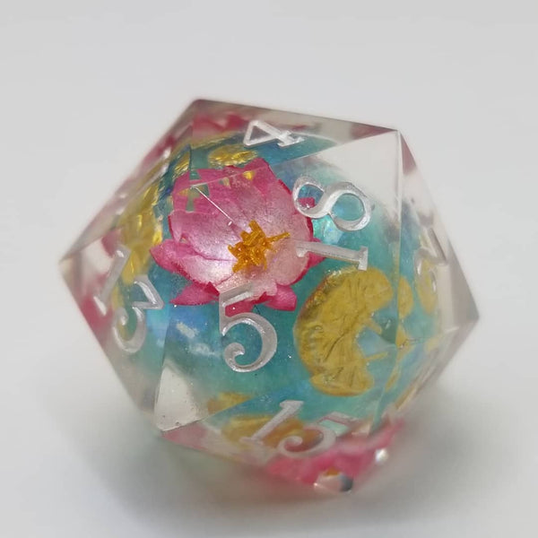 A clear D20 with a turquoise core and lily pad flowers inside. 