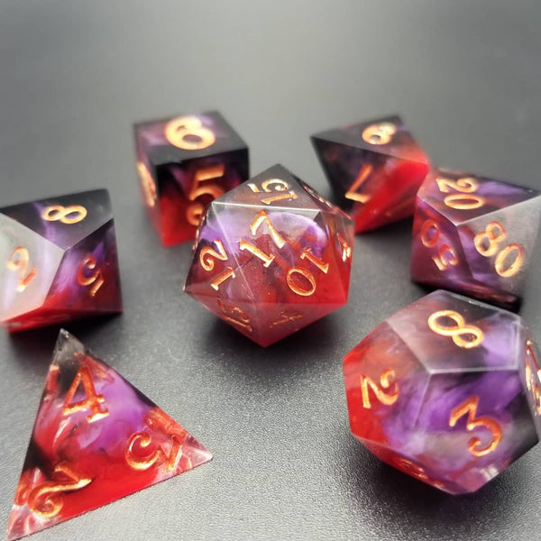 A set of black, purple and red resin dice with gold painted numbers.