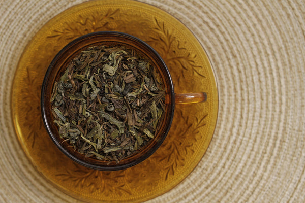 A top down view of a tea cup and saucer. Both the cup and saucer are made of amber glass. The cup is filled with the Ranger's Blend from Friday Afternoon Tea.