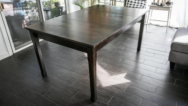 The Jasper gaming table with a dark finish sitting in a room with tiled floors.
