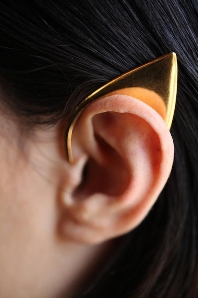 A picture of an ear wearing an ear cuff made out of gold in the shape of an elvin ear.