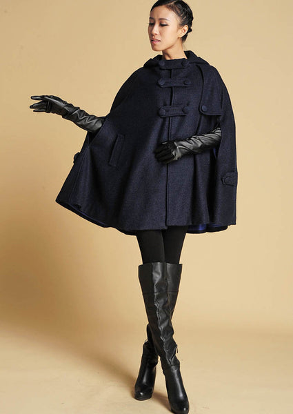 A woman wearing a thigh length wool cape in navy