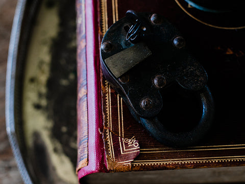 An old black lock sitting on top of an ornate book