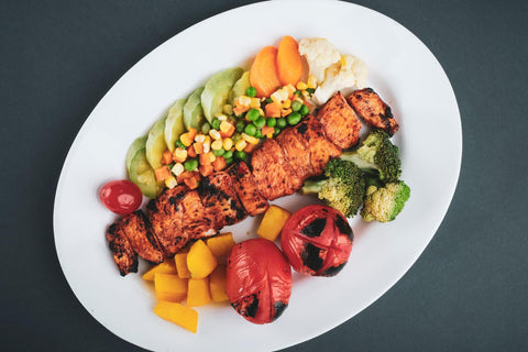 Grilled chicken served with veggies on a ceramic plate