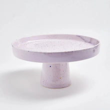 Load image into Gallery viewer, This is a pastel lilac hand painted, artisanal ceramic cake plate with colorful paint splatters measuring 11&quot; W x 4.75&quot; H is perfect for any home get-together
