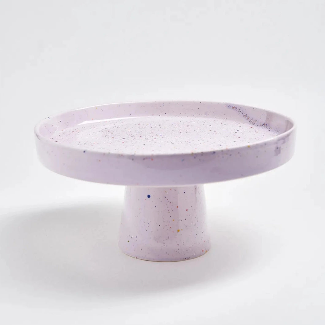 This is a pastel lilac hand painted, artisanal ceramic cake plate with colorful paint splatters measuring 11