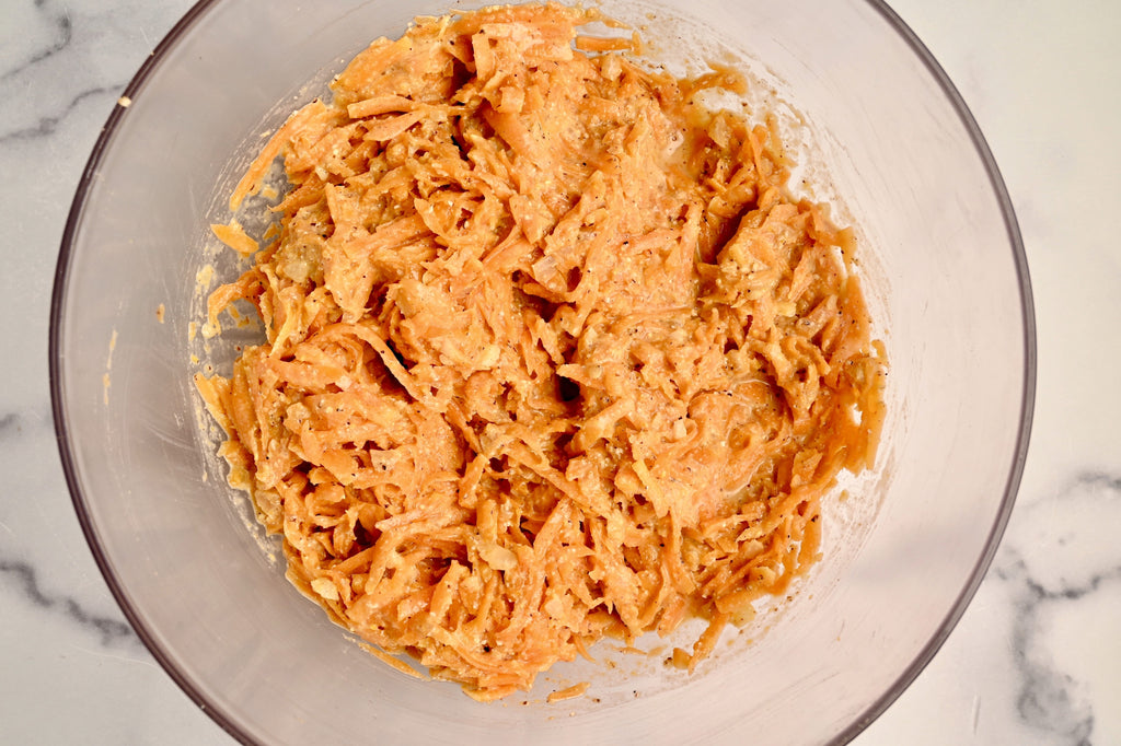 Shredded butternut squash in a clear glass mixing bowl