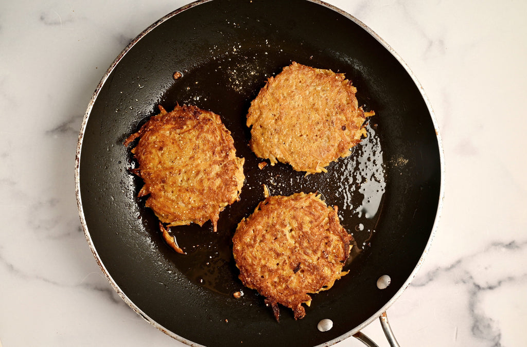 Butternut squash fritters frying in a cast iron skillet