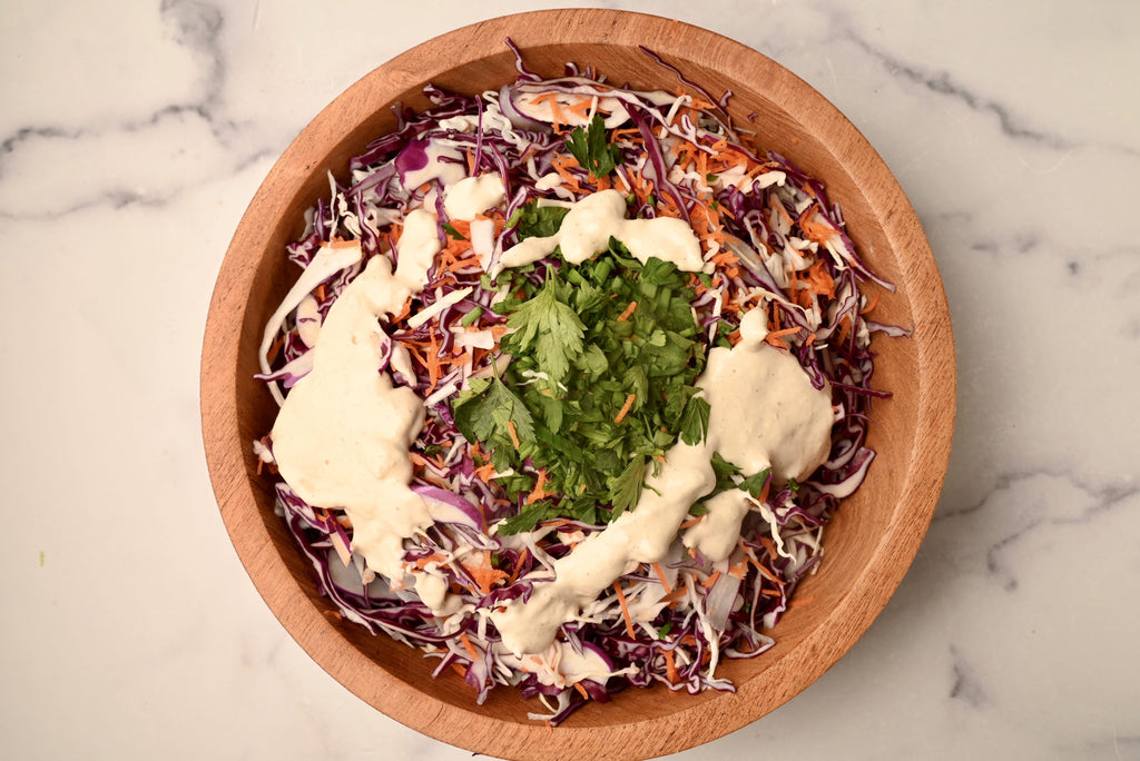 An overview of homemade coleslaw with dressing drizzled on top