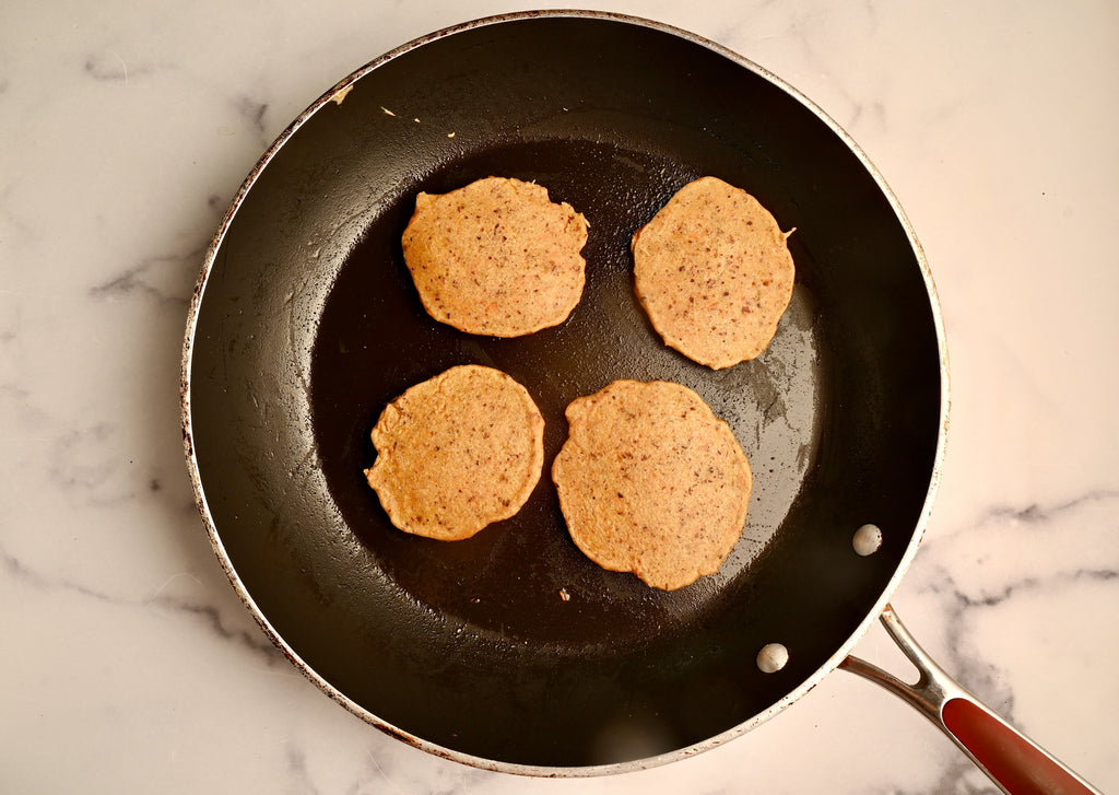 Mini carrot cake pancakes cooking in a black skillet